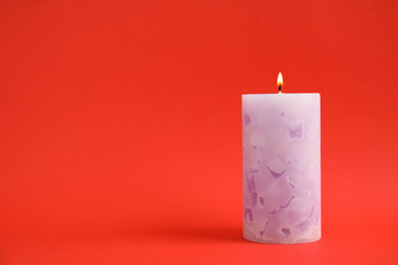 Alight wax candle on color background. Space for text