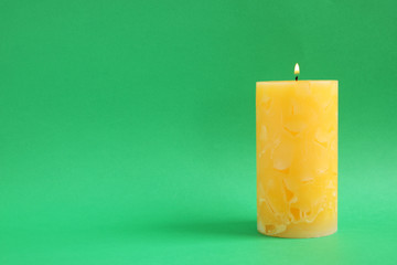 Alight wax candle on color background. Space for text