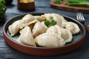 Plate of tasty dumplings served with parsley on table