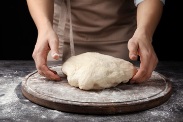 Female baker preparing bread dough at table, closeup