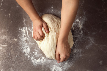 Fototapeta premium Female baker preparing bread dough at grey table, top view
