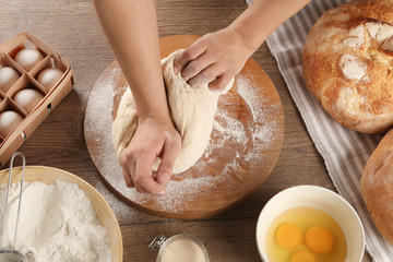 Female baker preparing bread dough at kitchen table, above view