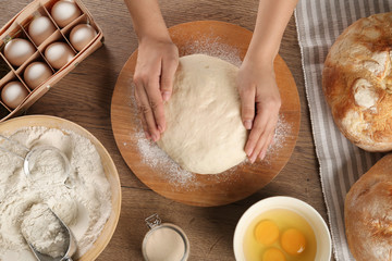 Female baker preparing bread dough at kitchen table, top view