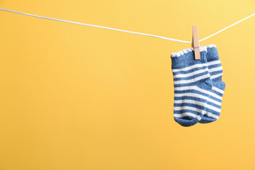 Small socks hanging on washing line against color background, space for text. Baby accessories