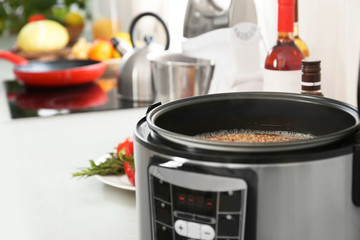 Modern multi cooker with buckwheat on table. Space for text