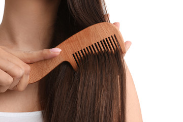 Young woman with wooden hair comb on white background, closeup