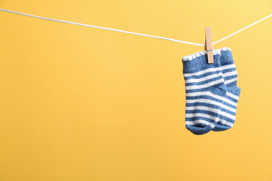 Small socks hanging on washing line against color background, space for text. Baby accessories