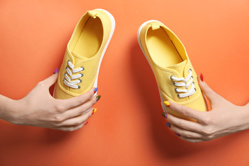 Young woman holding new sneakers on color background, closeup
