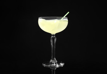 Glass of delicious cucumber martini with ice on dark background