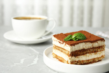 Tiramisu cake with cup on table against light background, space for text