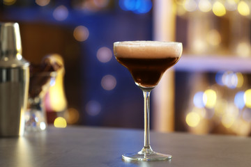 Glass of Espresso Martini on counter in bar, space for text. Alcohol cocktail