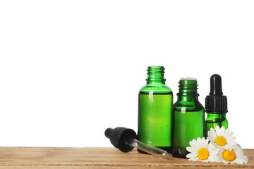 Chamomile flowers and cosmetic bottles of essential oil on wooden table against white background. Space for text