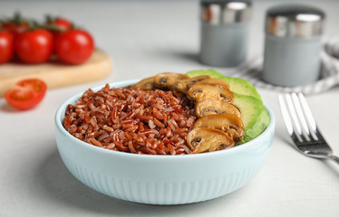 Bowl of brown rice with mushrooms and avocado on table, closeup