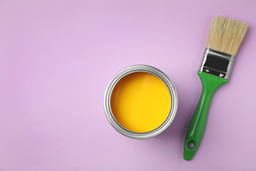Open can with paint and brush on color background, top view. Space for text