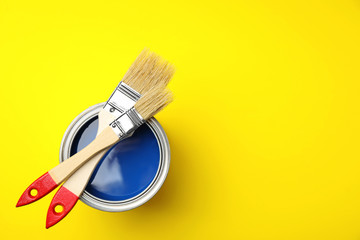 Open cans with paint and brushes on color background, top view. Space for text
