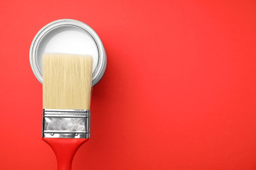 Open can with paint and brush on color background, top view. Space for text