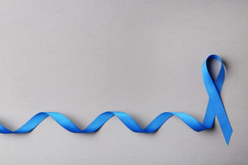 Blue ribbon on color background, top view with space for text. Colon cancer awareness concept