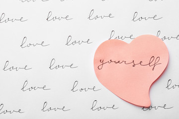 Composition with words LOVE YOURSELF and paper heart on white background, top view