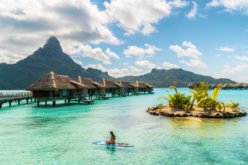 Tahiti luxury resort hotel in Bora Bora ,French Polynesia. Paddleboard leisure activity SUP paddle woman on active vacation in Tahiti, French Polynesia. Mount Otemanu summer holiday. - obrazy, fototapety, plakaty