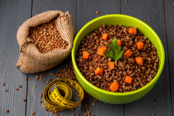 Green bowl of tasty buckwheat porridge on gray wooden table. The concept of a healthy diet. Top view.