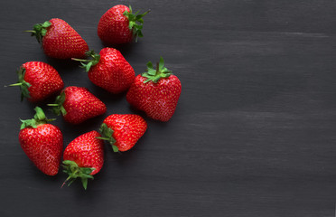 Pile of ripe strawberries on black background with copy space