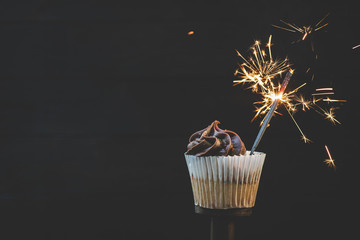 Cupcake with chocolate icing and a lit sparkler