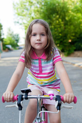 Children learning to drive a bicycle on a driveway outside. Little girls riding bikes on asphalt road in the city. . Active healthy outdoor sports for young children. Fun activity for the baby concept