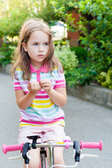 Children ride a bike near the house.  A little girl on a Bicycle on a Sunny summer day. Active healthy outdoor sports for young children. Fun activity for the baby concept