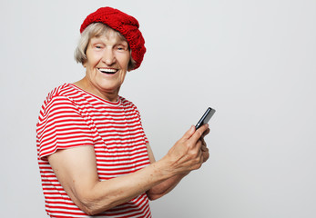 lifestyle, family  and people concept: old grandmother is talking to her grandchildren by phone, smiling and greeting them.