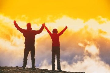 Success people reaching goal achievement - winning couple hikers with arms up in victory happy together to accomplish life dream, Travel adventure hiking tourists at sunset.