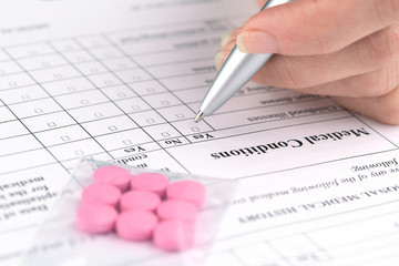 Pink pills and hand writing on medical questionnaire form