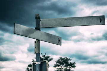 Blank directional road signs. Black metal arrows on the signpost. Warm toned colors. Old style image