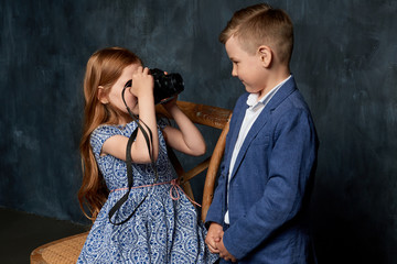 red-haired girl with a retro camera takes pictures of a boy