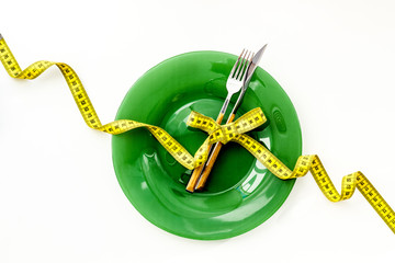 Slim concept with plate, flatware and measuring tape on white background top view