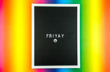 The word FRIDAY on a letter board with happy smiley emoji against multicolor background