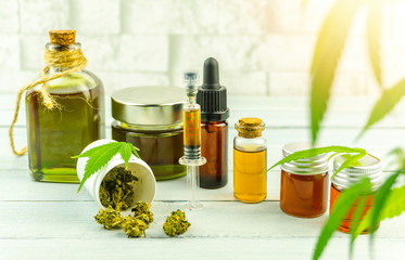 CBD cannabidiol oil glass bottles, pills flower buds and Cannabis leafs on bright wooden backdrop