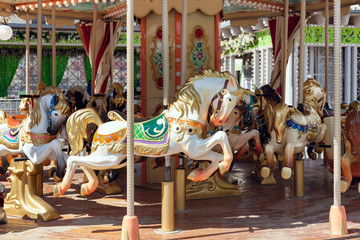 Children's Carousel With Horses In An Amusement Park. Empty Carousel On Clear Sunny Summer Day.
