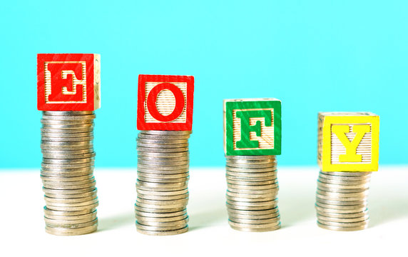 End of Financial Year and savings concept stacking coins with EOFY building blocks.