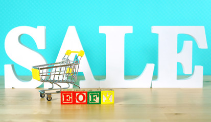 End of Financial Year sales shopping concept with mini shopping cart and large sale letters.
