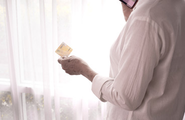 businesswoman hold credit card and using phone on white curtain window background.