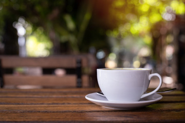 wood table with cup of latte coffee in morning garden.