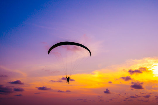 paraglider flying on sky at sunset