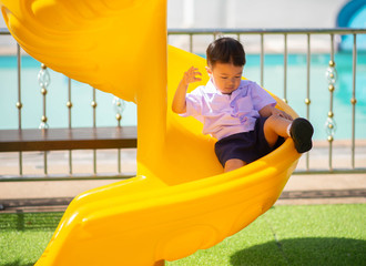 Little Asian boy playing slider at playground kindergarten school