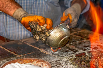 Cropped image of the traditional Turkish tinsmith covering the copper object with tin over fire. 