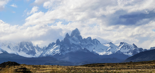 a panoramic view of The mount Fitz Roy over the blue sky with some clouds
