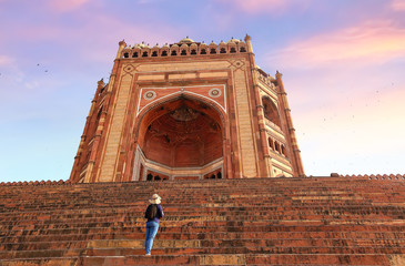 Fatehpur Sikri - Female tourist looks up at the giant Mughal architecture gateway known as the...