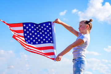 American flag. Happy little patriotic girl holding USA flag waving on blue sky background. National 4 july. Memorial day