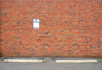 no parking sign on the brick wall in the parking space