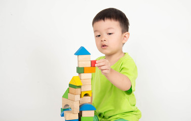 Little Asian toddler boy playing wood blocks wear helmet engineer