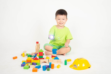 Little Asian toddler boy playing wood blocks wear helmet engineer